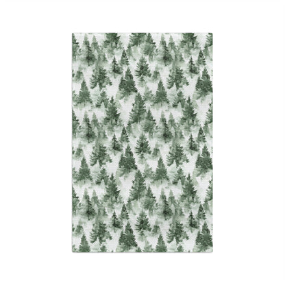 Microfiber tea towel with a painterly deep-green evergreen forest pattern on a white background.