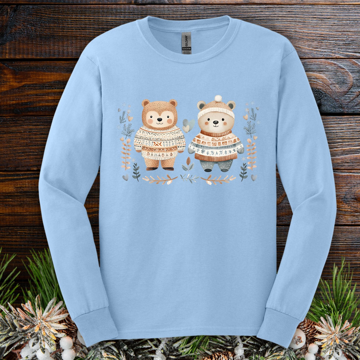 Light blue long sleeve tee with two watercolor bears in fair isle sweaters, winter foliage.