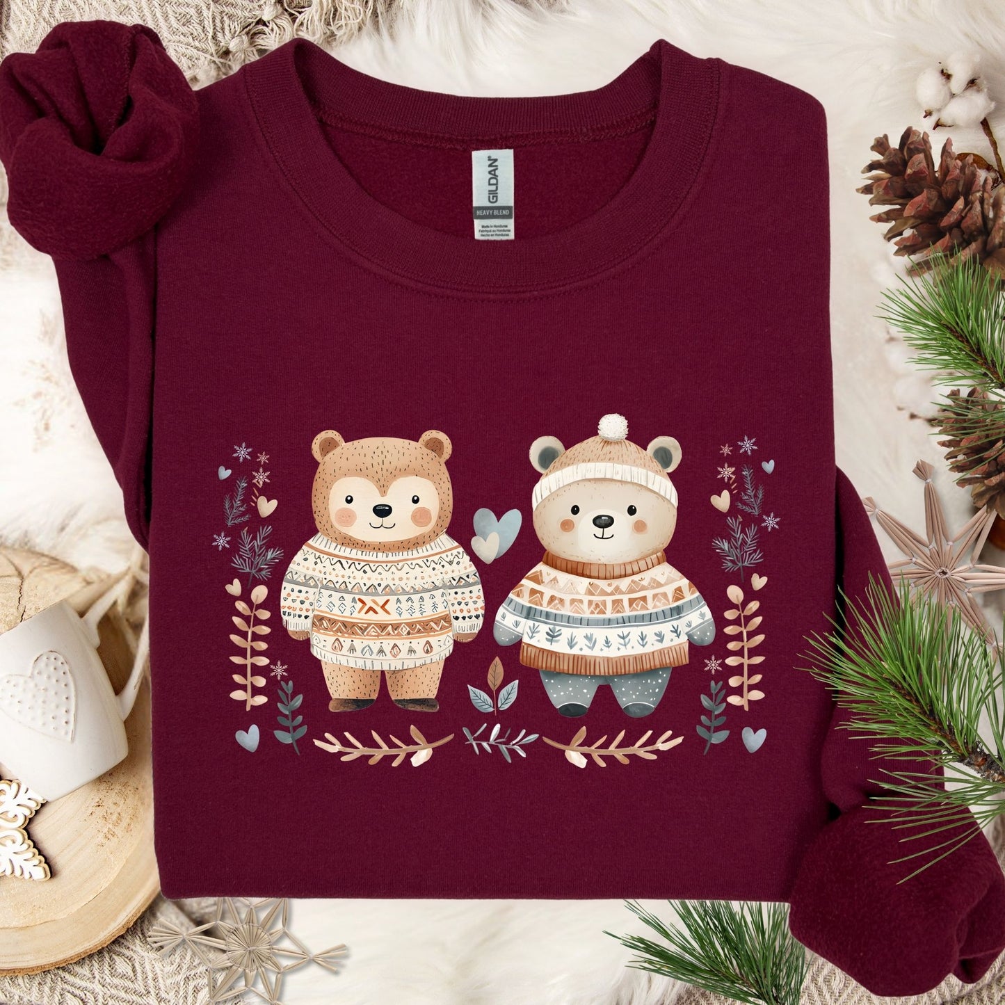 Maroon heavy blend sweatshirt with two love bears in Fair Isle sweaters, winter foliage, and snowflakes.