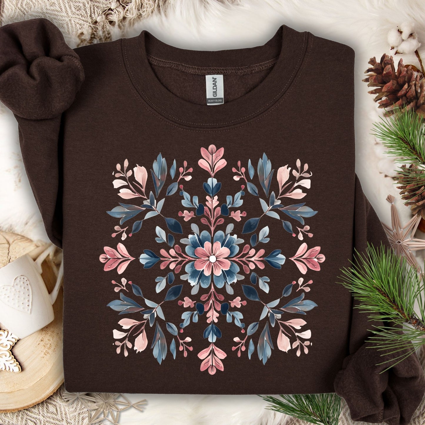 Dark chocolate Gildan sweatshirt with a pink and blue floral snowflake mandala design, surrounded by winter decor.