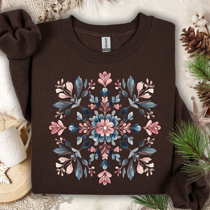 Dark chocolate Gildan sweatshirt with a pink and blue floral snowflake mandala design, surrounded by winter decor.