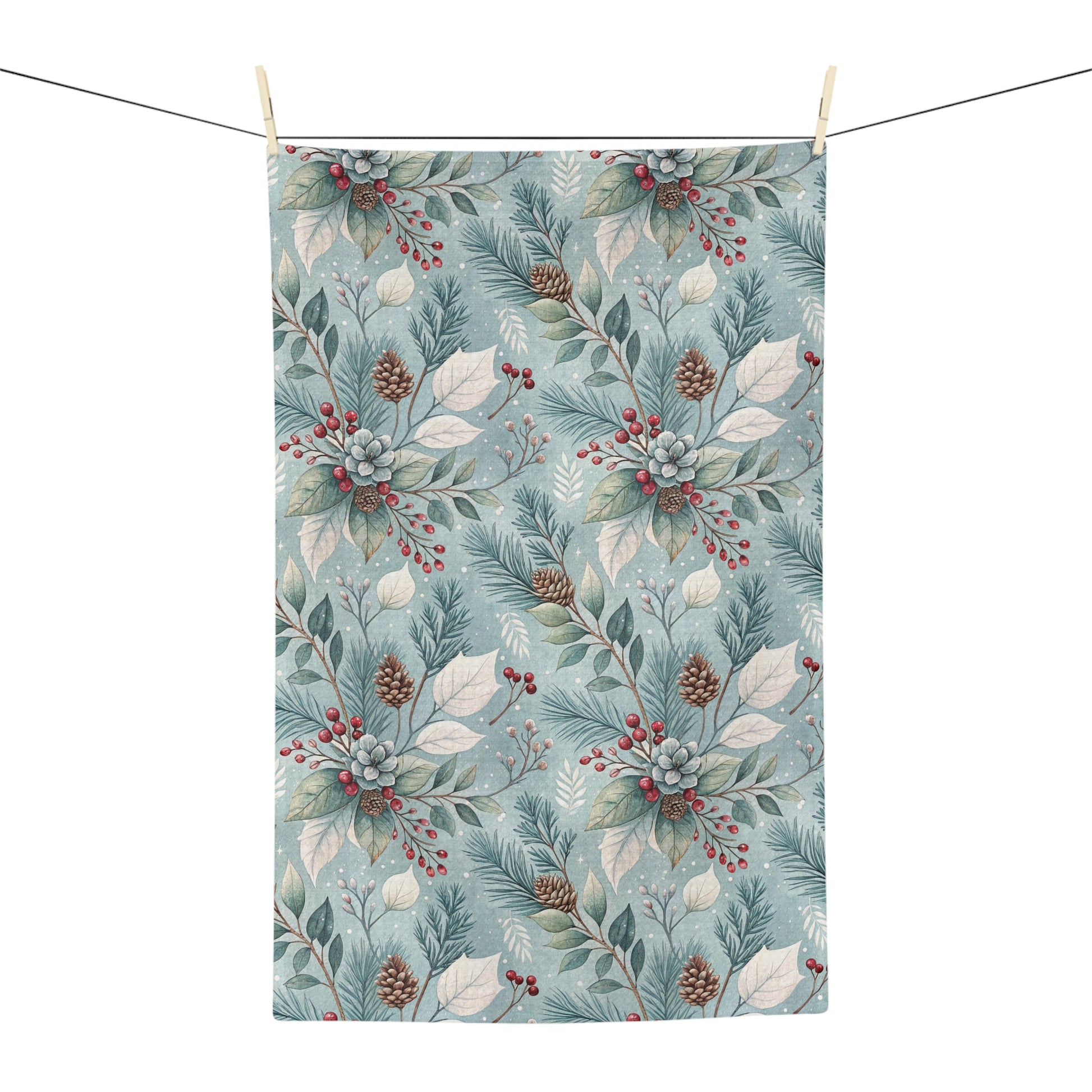 Microfiber tea towel with a repeating winter foliage pattern of teal sprigs, frosted leaves, pinecones, and red berries.