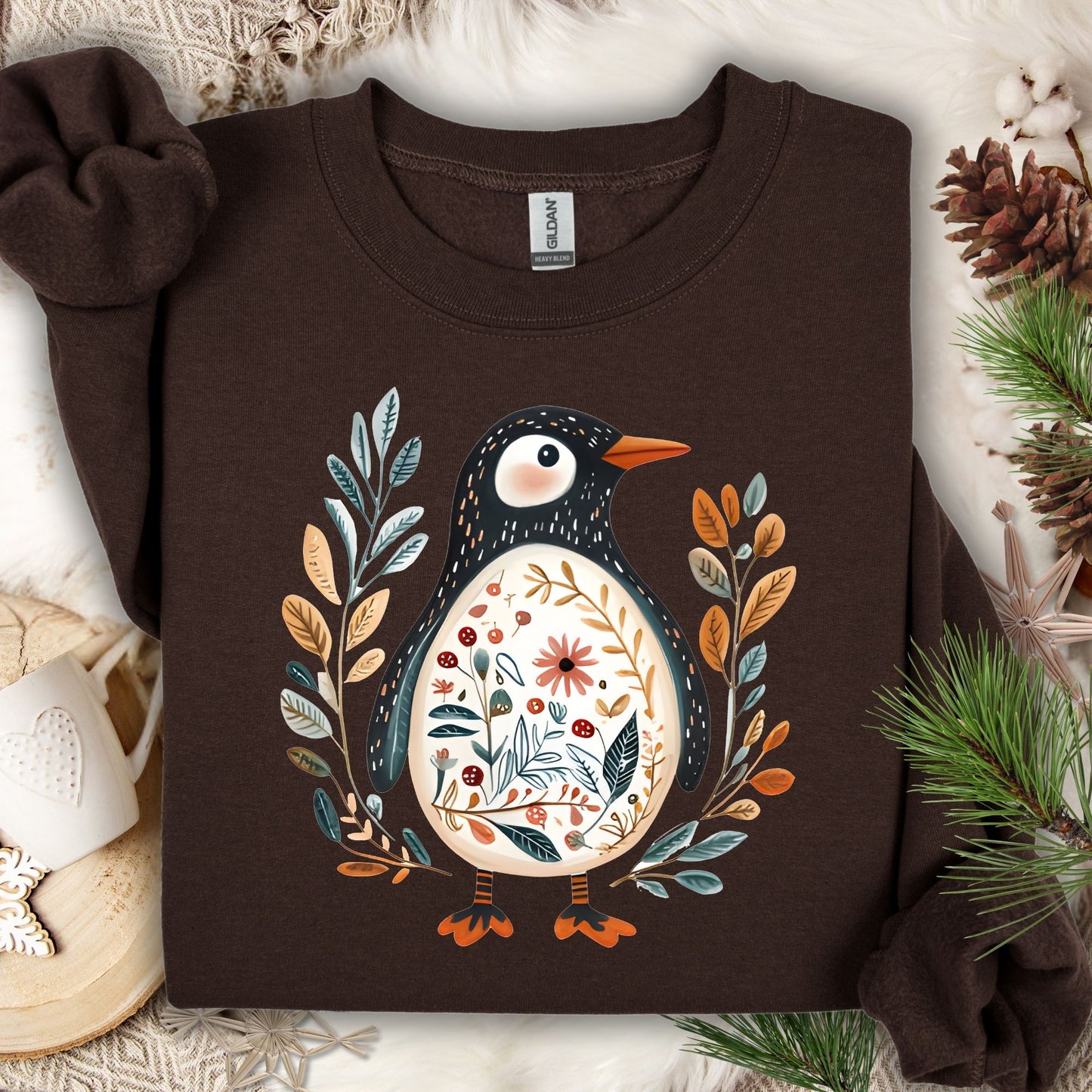 Dark chocolate sweatshirt with a folk art penguin adorned with botanical patterns and leafy sprigs.