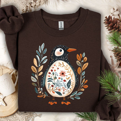 Dark chocolate sweatshirt with a folk art penguin adorned with botanical patterns and leafy sprigs.
