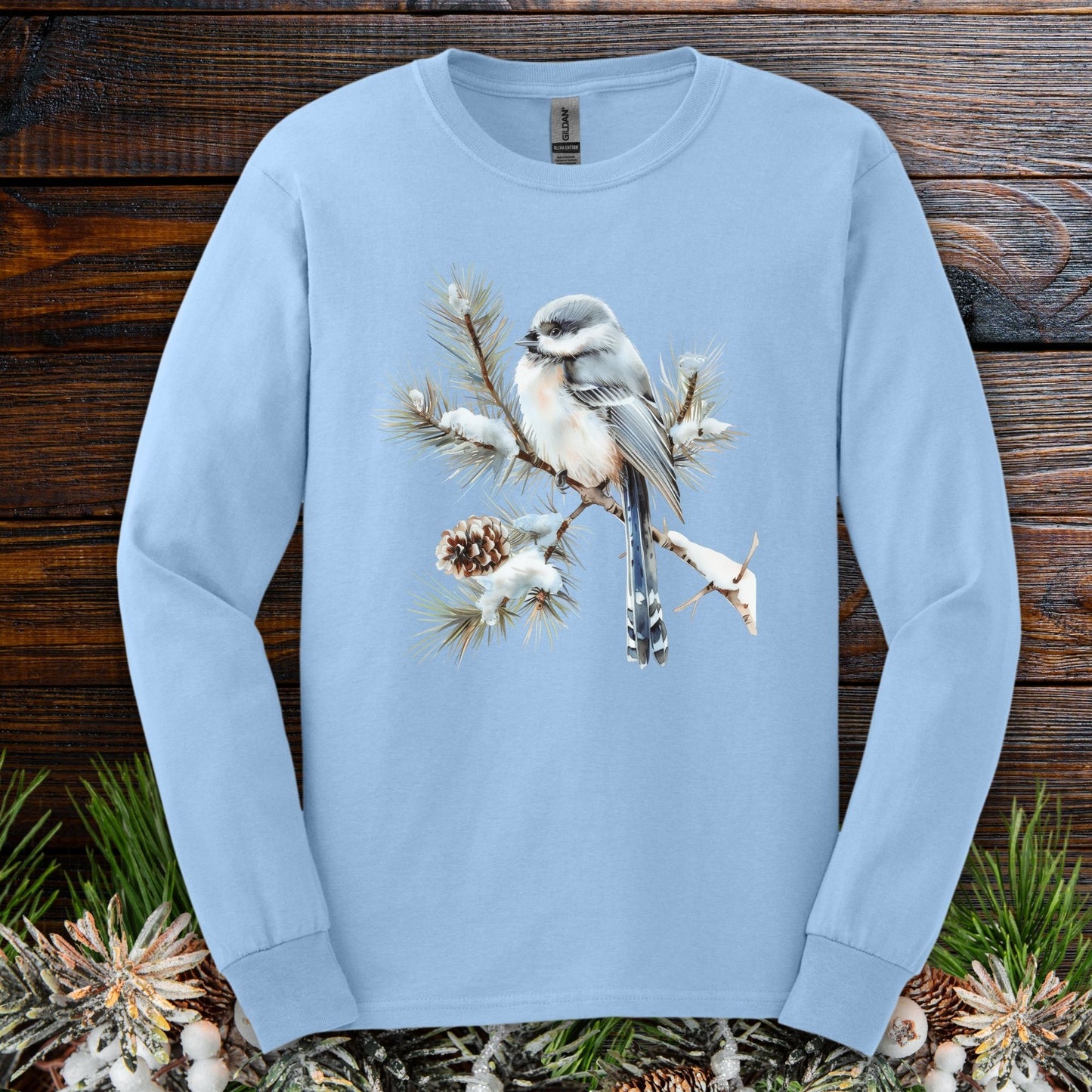 Light blue Gildan long sleeve tee with a watercolor long-tailed tit on a snowy evergreen branch.