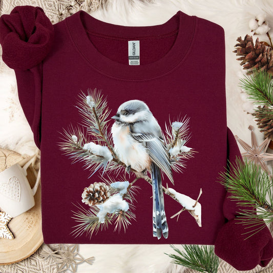Maroon Gildan sweatshirt with a watercolor long-tailed tit on a snow-tipped evergreen bough.