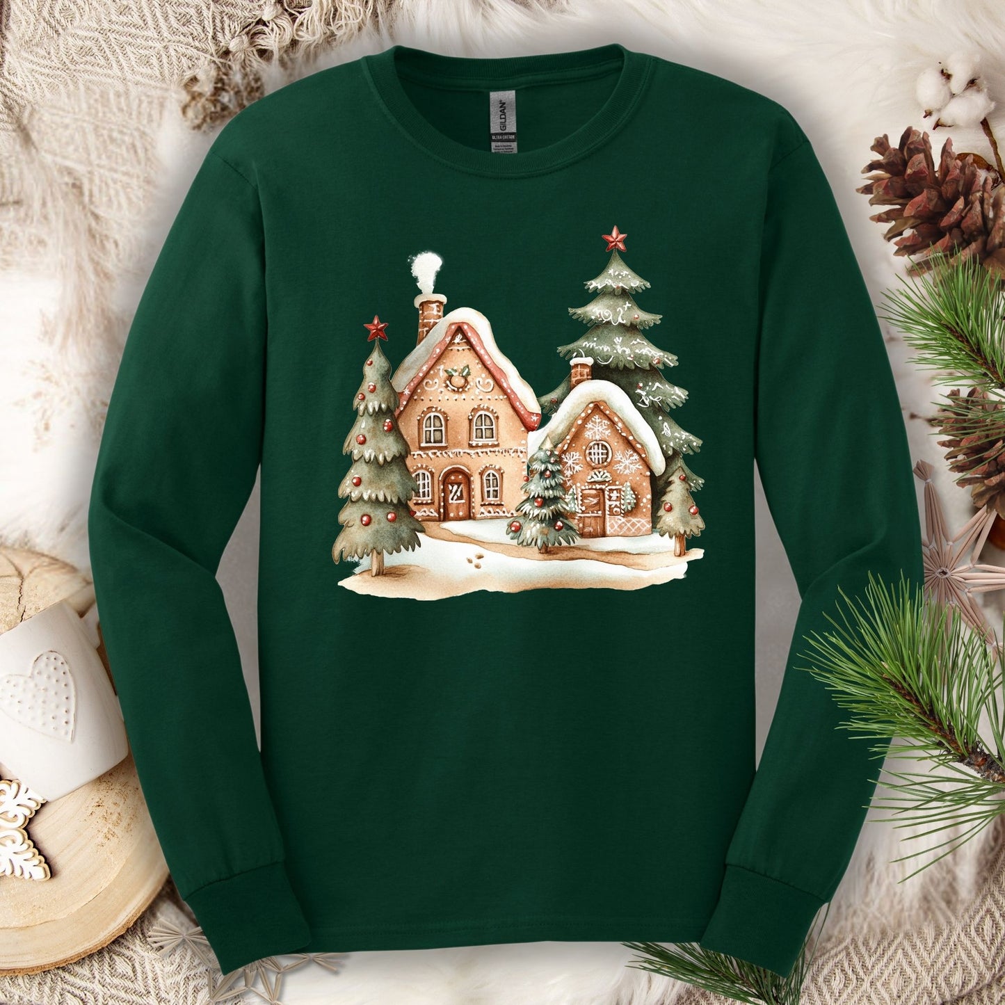 Forest Green long sleeve tee with a watercolor gingerbread house and snowy evergreen trees design.