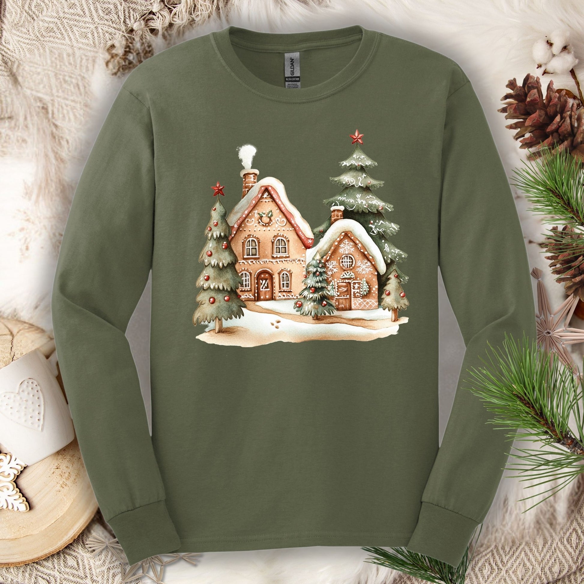 Military Green Gildan 2400 long sleeve tee with watercolor gingerbread houses and snowy evergreens.