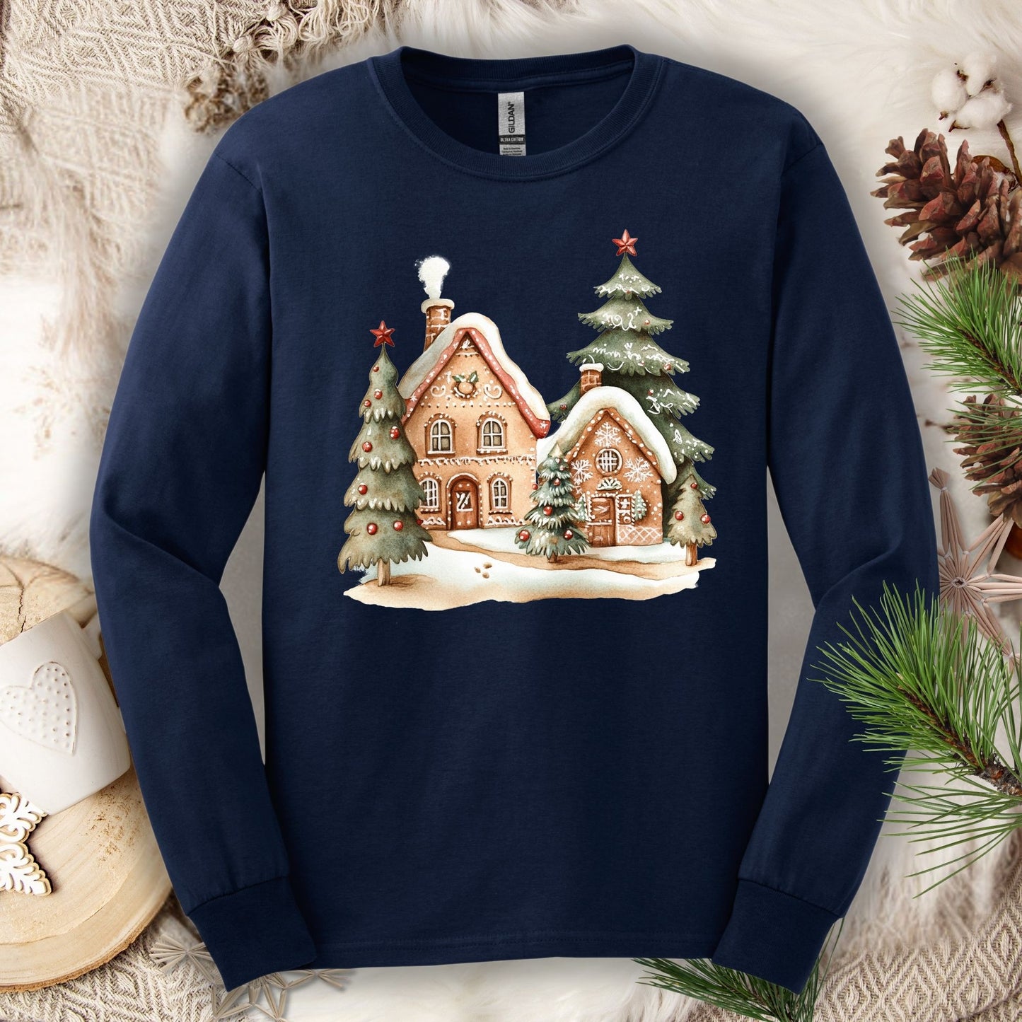 Navy long sleeve tee with a watercolor gingerbread house and snowy evergreen design.