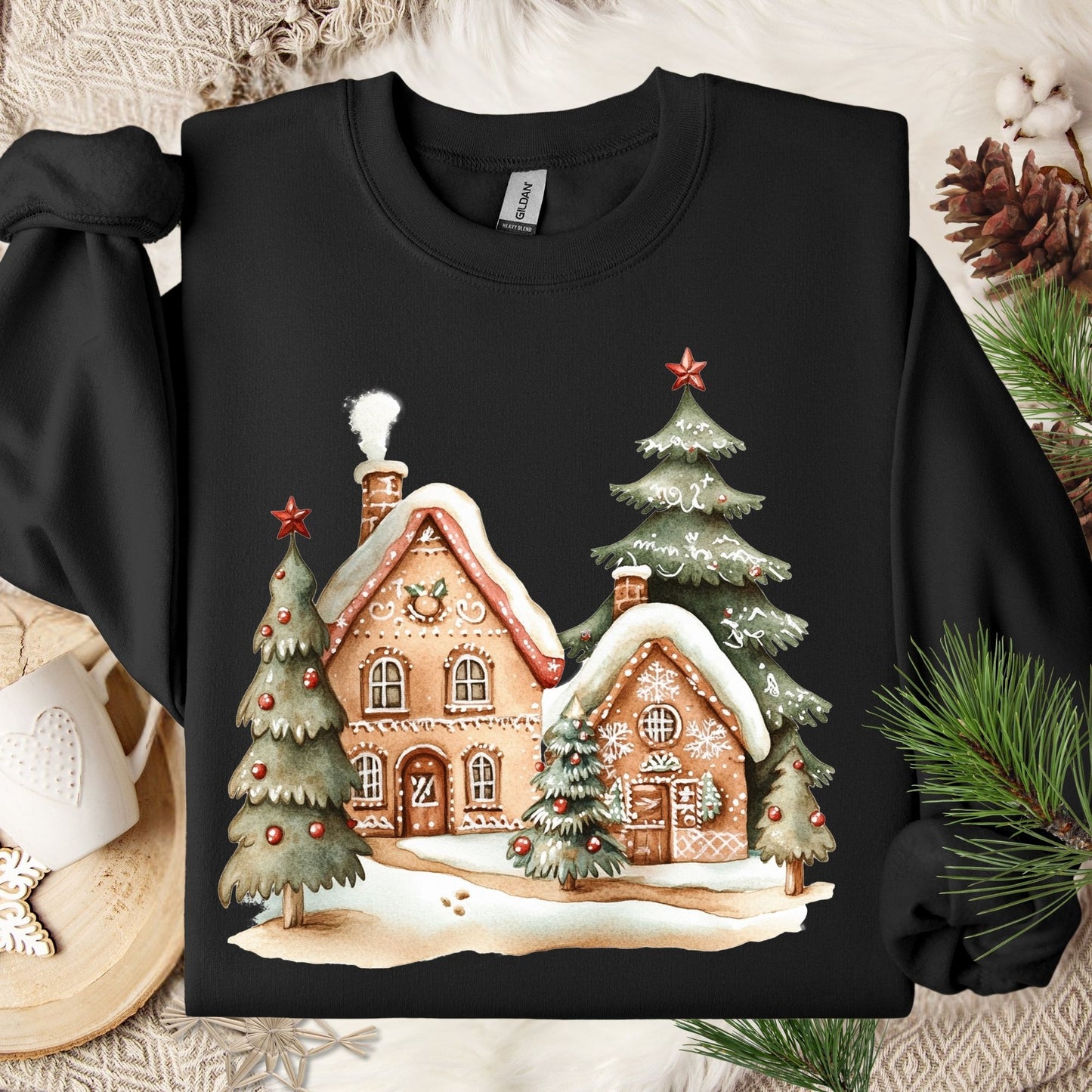 Black Gildan 18000 sweatshirt with a whimsical gingerbread village and snow-dusted Christmas trees design.