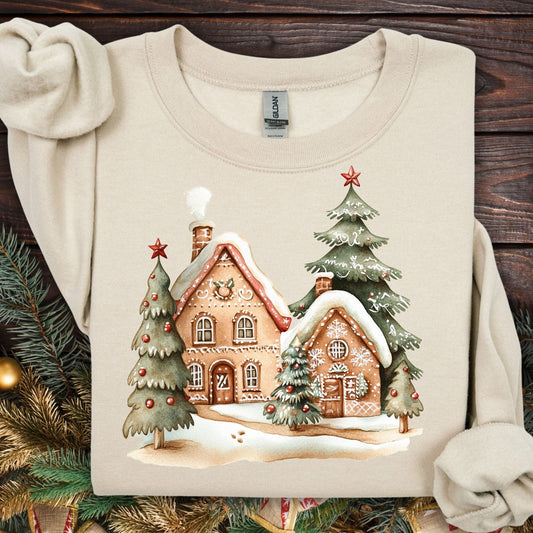 Sand Gildan 18000 sweatshirt with two gingerbread houses and Christmas trees in a snowy scene.