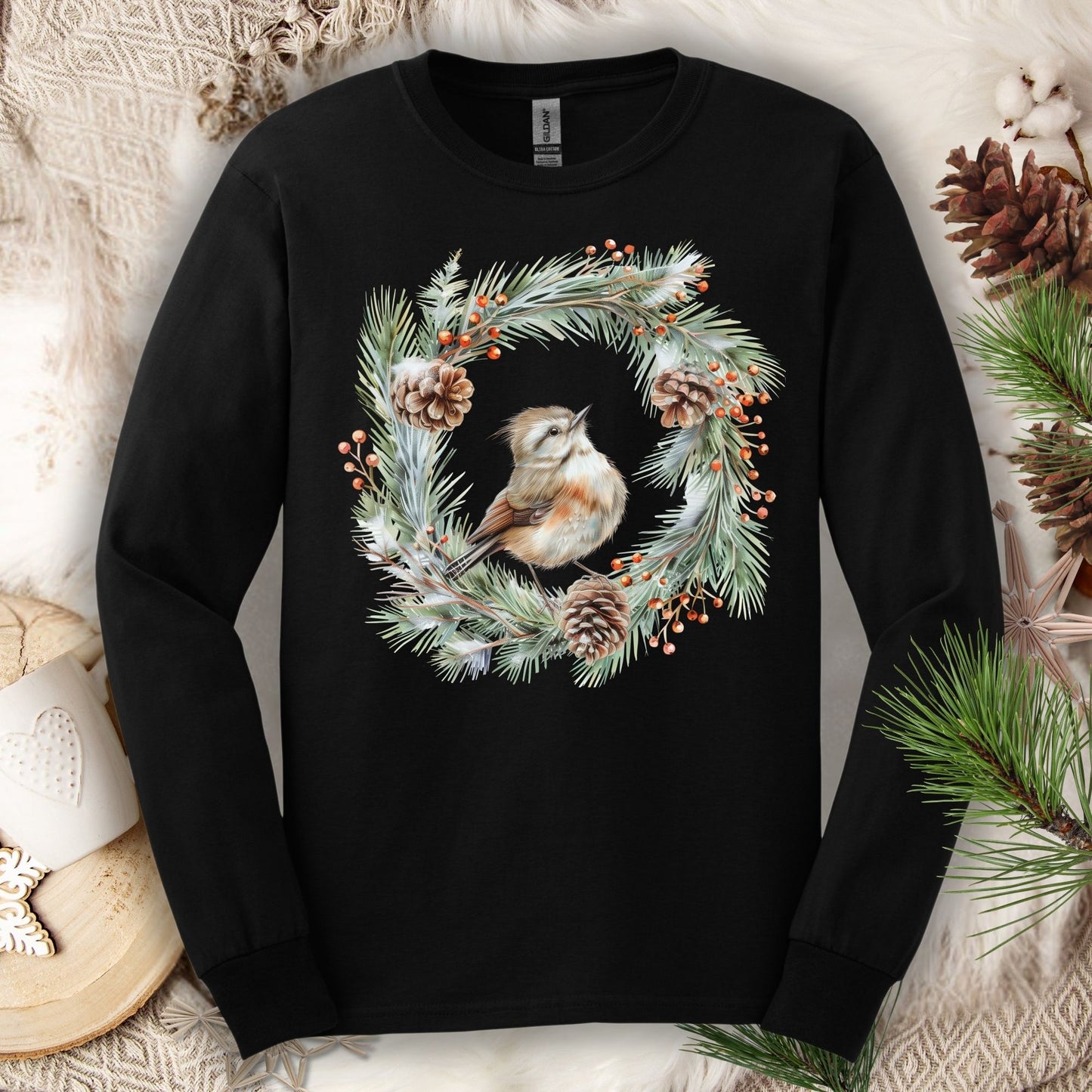 Black long sleeve tee with a watercolor winter wren in an evergreen wreath with pinecones and berries.