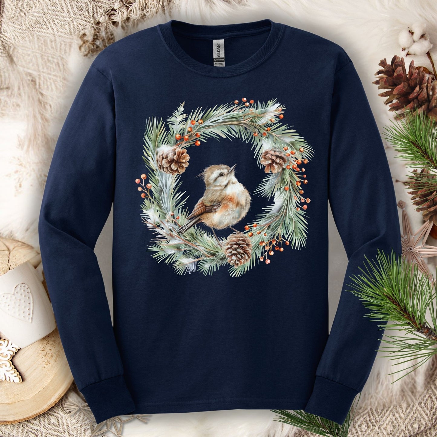 Navy long sleeve tee with a watercolor winter wren in an evergreen and pinecone wreath.