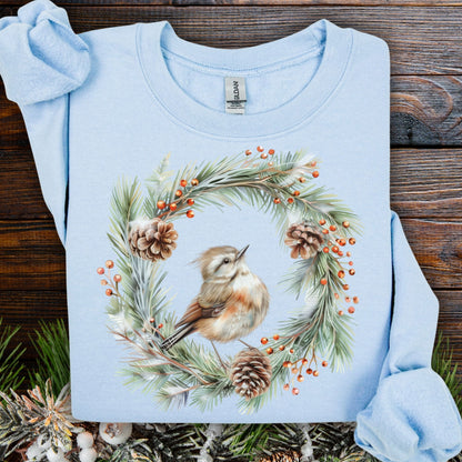 Light blue cotton-polyester sweatshirt with a watercolor wren in an evergreen wreath with pinecones and berries.