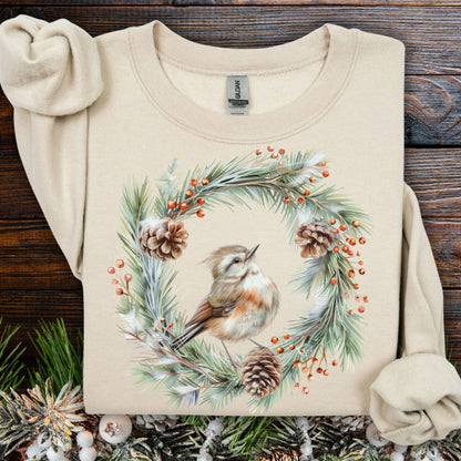 Sand crewneck sweatshirt with a watercolor wren in an evergreen wreath, pinecones, and red berries.