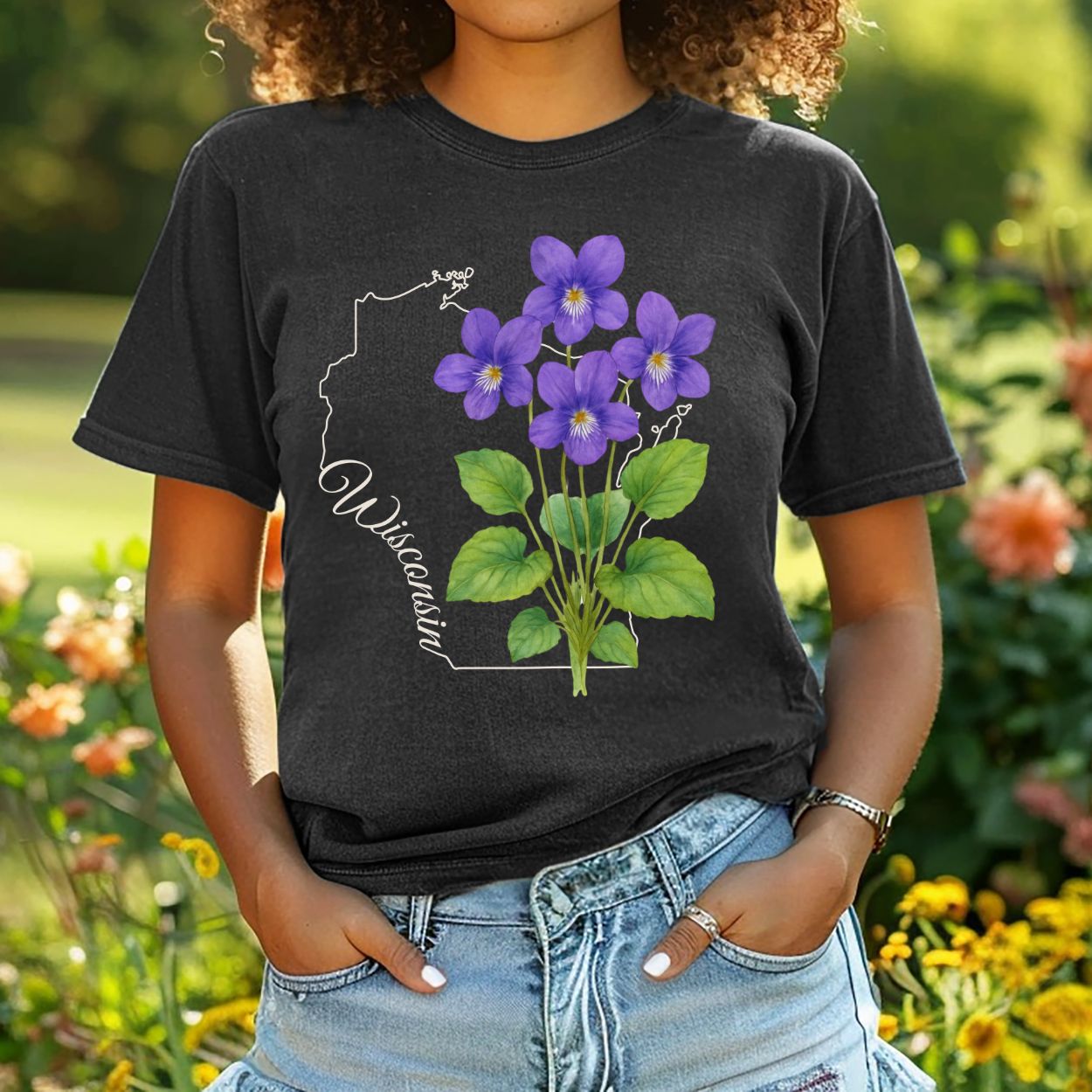 Garment-dyed black t-shirt with a watercolor wood violet cluster over a subtle Wisconsin outline.