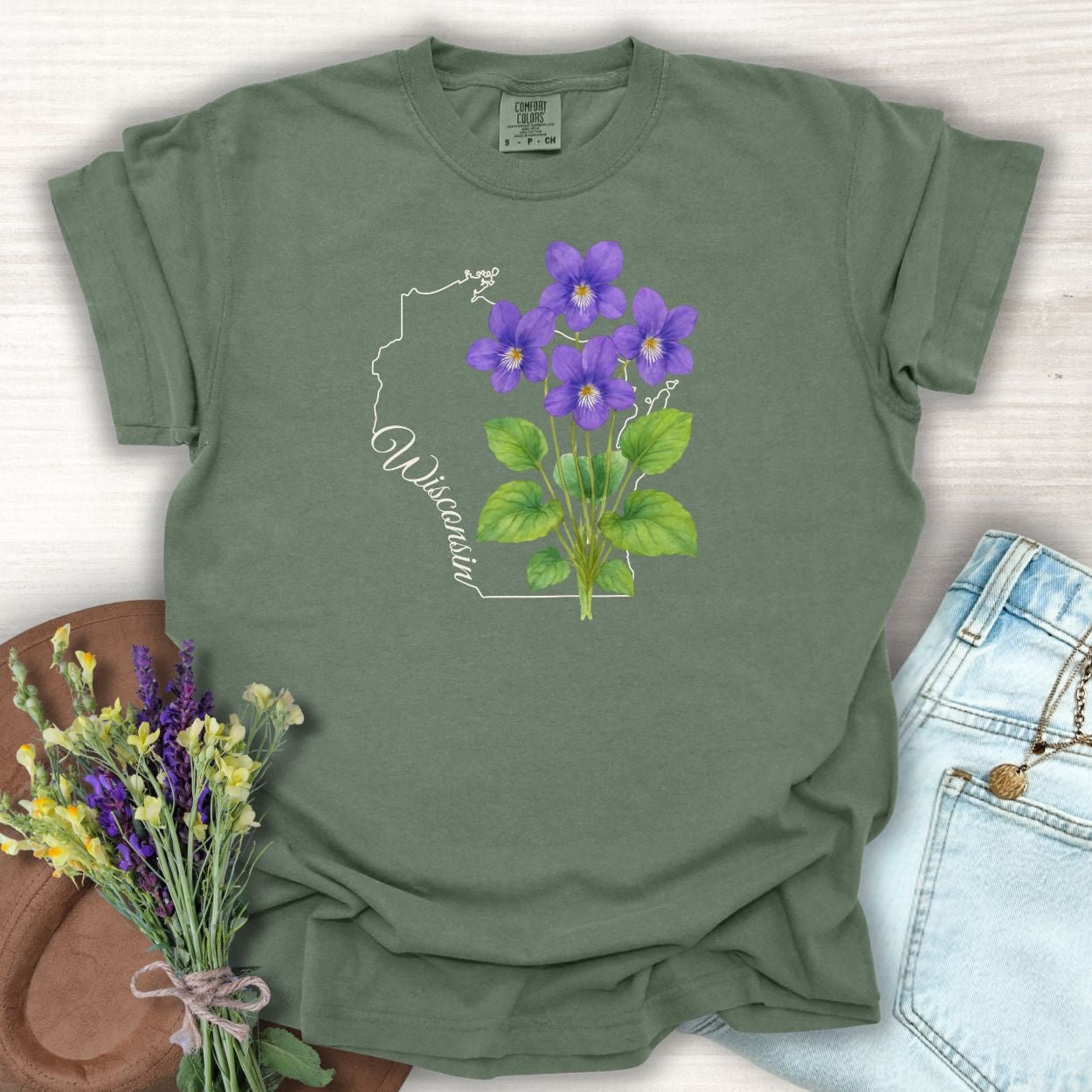 Moss green garment-dyed cotton t-shirt with a watercolor wood violet cluster and "Wisconsin" script over a state outline.