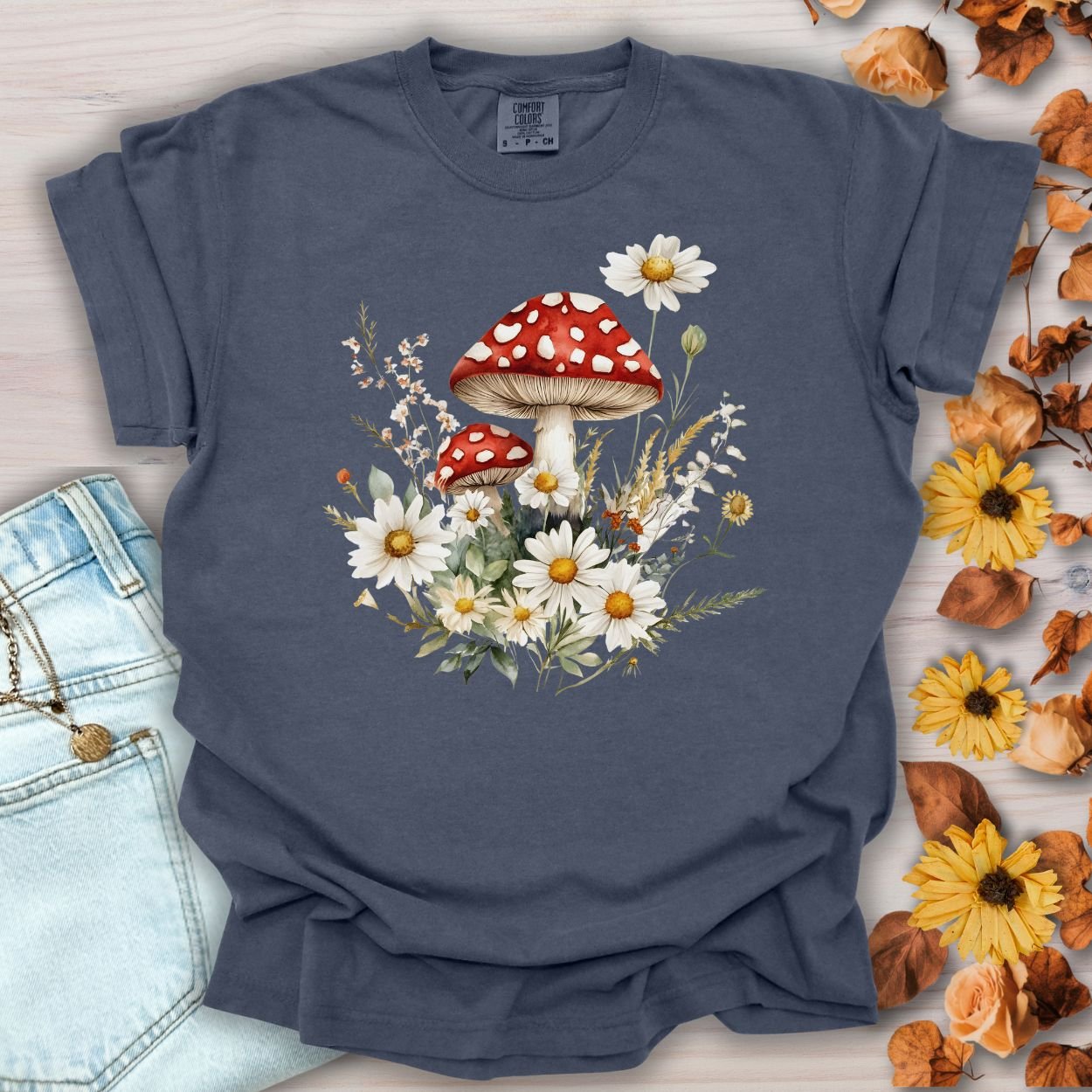 Denim blue garment-dyed t-shirt with a vintage-inspired red mushroom and daisy floral illustration.