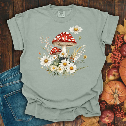 Bay green garment-dyed cotton t-shirt with a vintage floral mushroom illustration, next to jeans and fall decor.