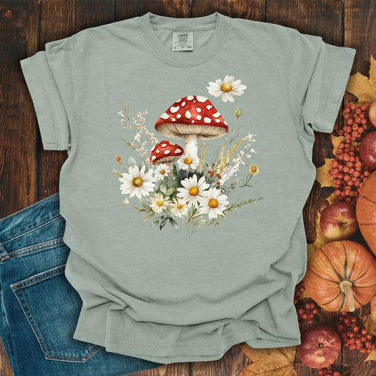 Bay green garment-dyed cotton t-shirt with a vintage floral mushroom illustration, next to jeans and fall decor.