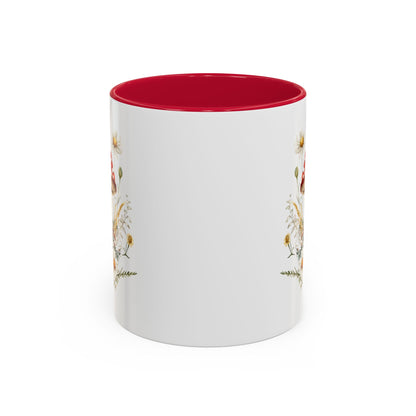 White ceramic mug with a red interior and handle, featuring a watercolor print of red-capped mushrooms, daisies, and wild grasses.