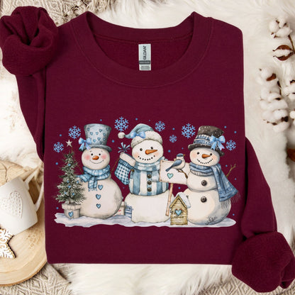 Maroon heavy blend sweatshirt with watercolor woodland snowmen, blue hats, scarves, birdhouse, and birds.