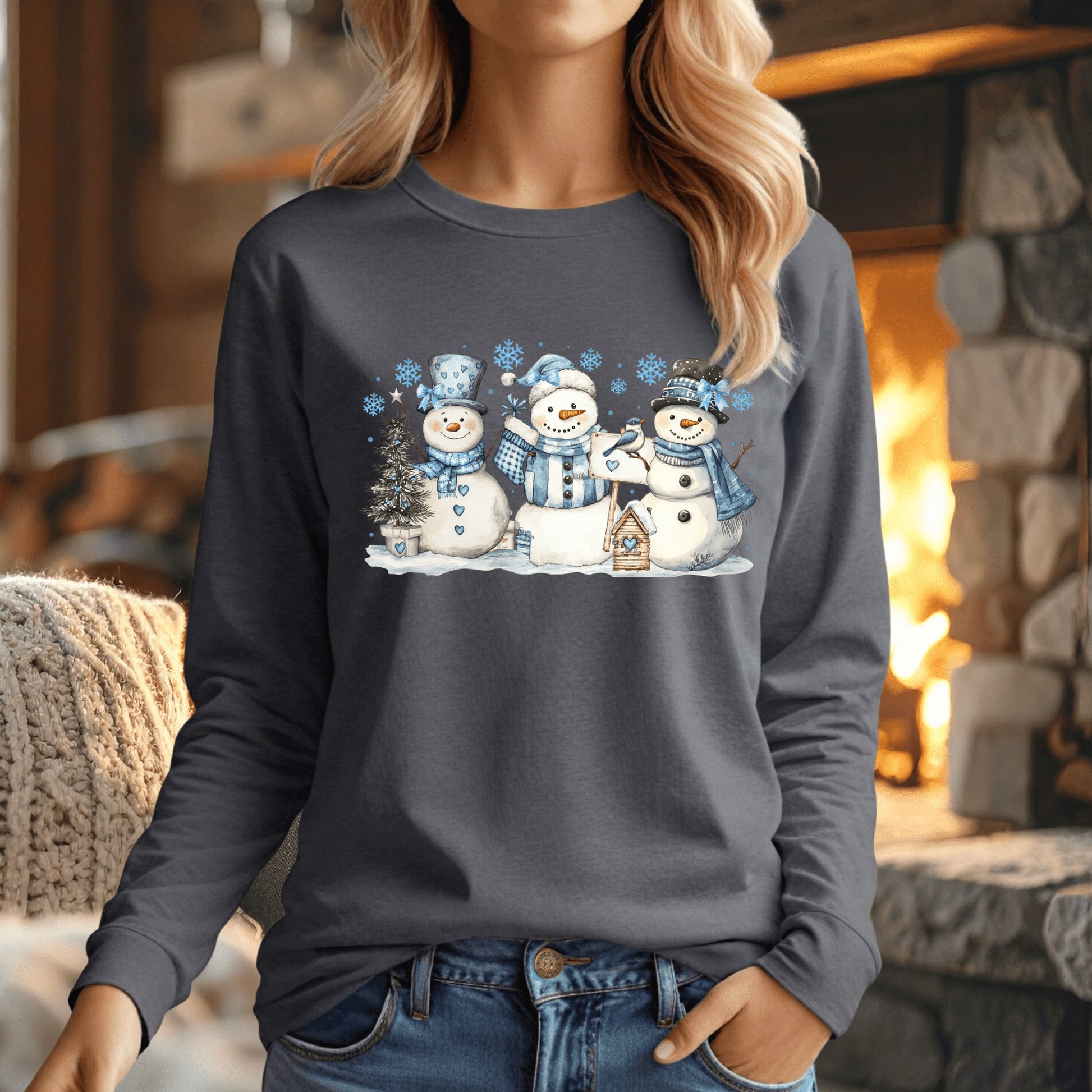 Charcoal long-sleeve tee with watercolor woodland snowmen, blue hats, scarves, and a birdhouse.