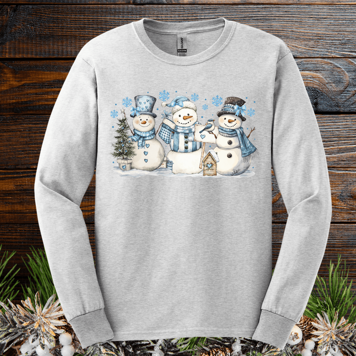 Light gray long sleeve tee with watercolor woodland snowmen, blue hats, scarves, and snowflakes.