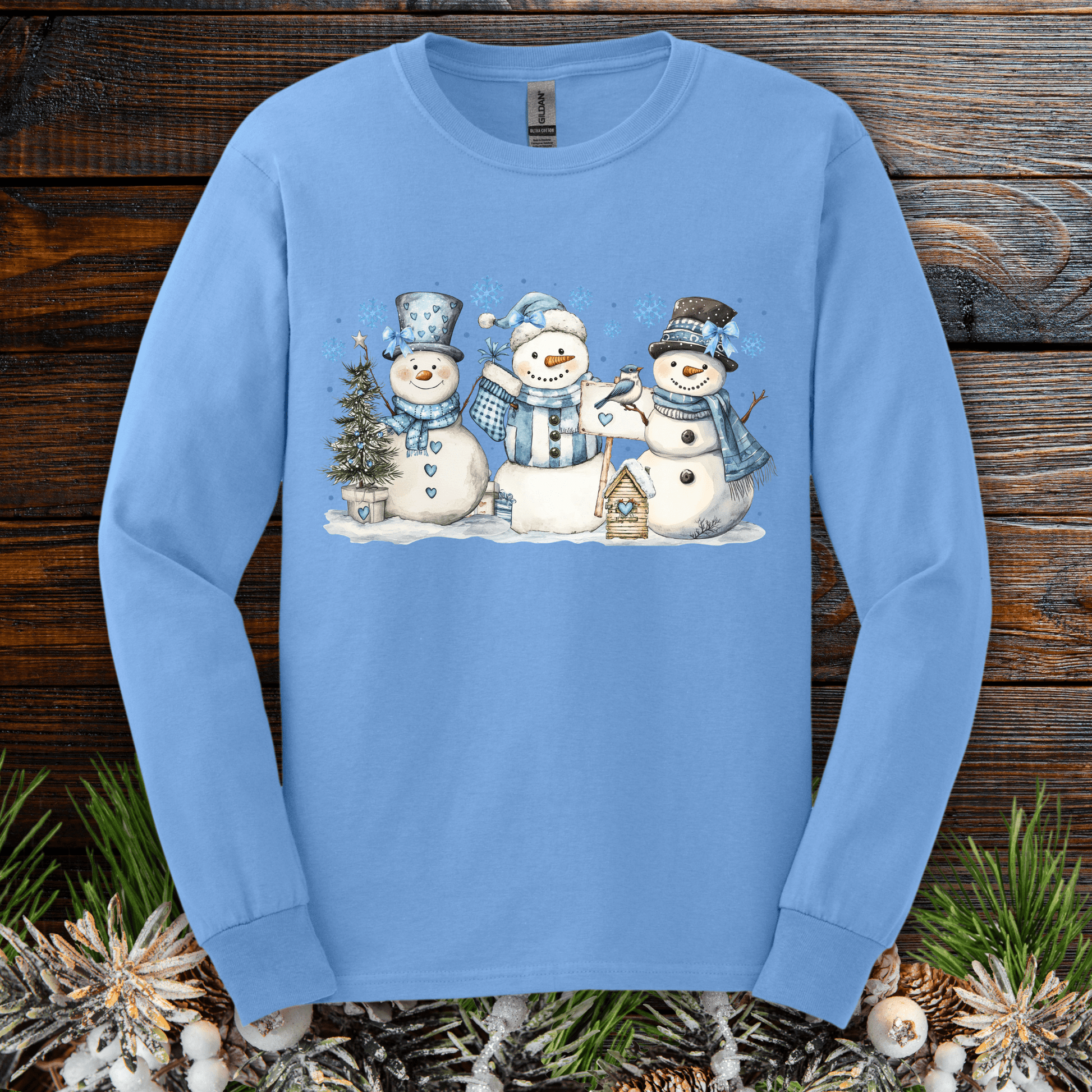 Carolina Blue long sleeve tee with three watercolor snowmen, blue hats, scarves, and a birdhouse.