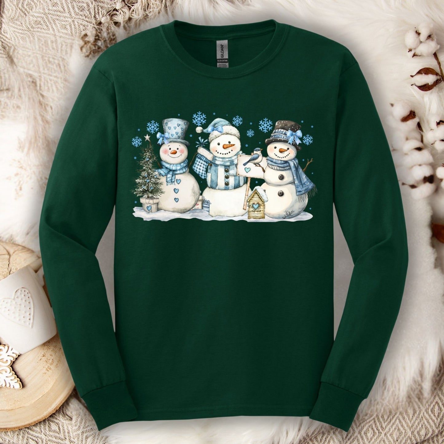 Forest Green long sleeve tee with three watercolor snowmen, blue hats, scarves, and snowflakes.