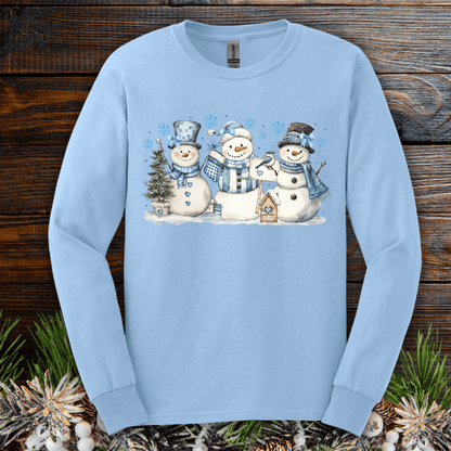 Light blue long sleeve tee with three watercolor snowmen, blue hats, scarves, and a birdhouse.