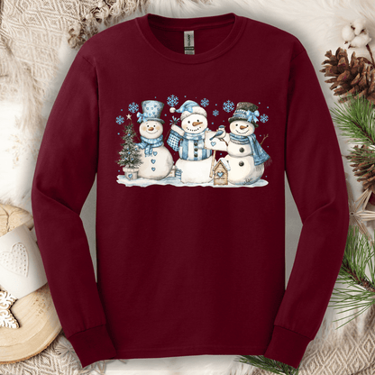 Maroon long sleeve tee with watercolor snowmen, blue hats/scarves, birdhouse, and snowflakes.