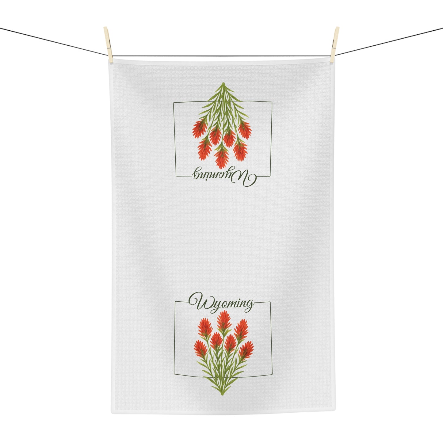 White microfiber tea towel with two red Indian Paintbrush flower designs and "Wyoming" script.