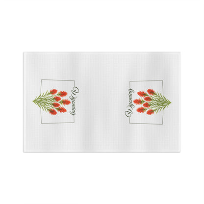 White microfiber tea towel with two red Indian paintbrush sprigs and "Wyoming" in a square frame.
