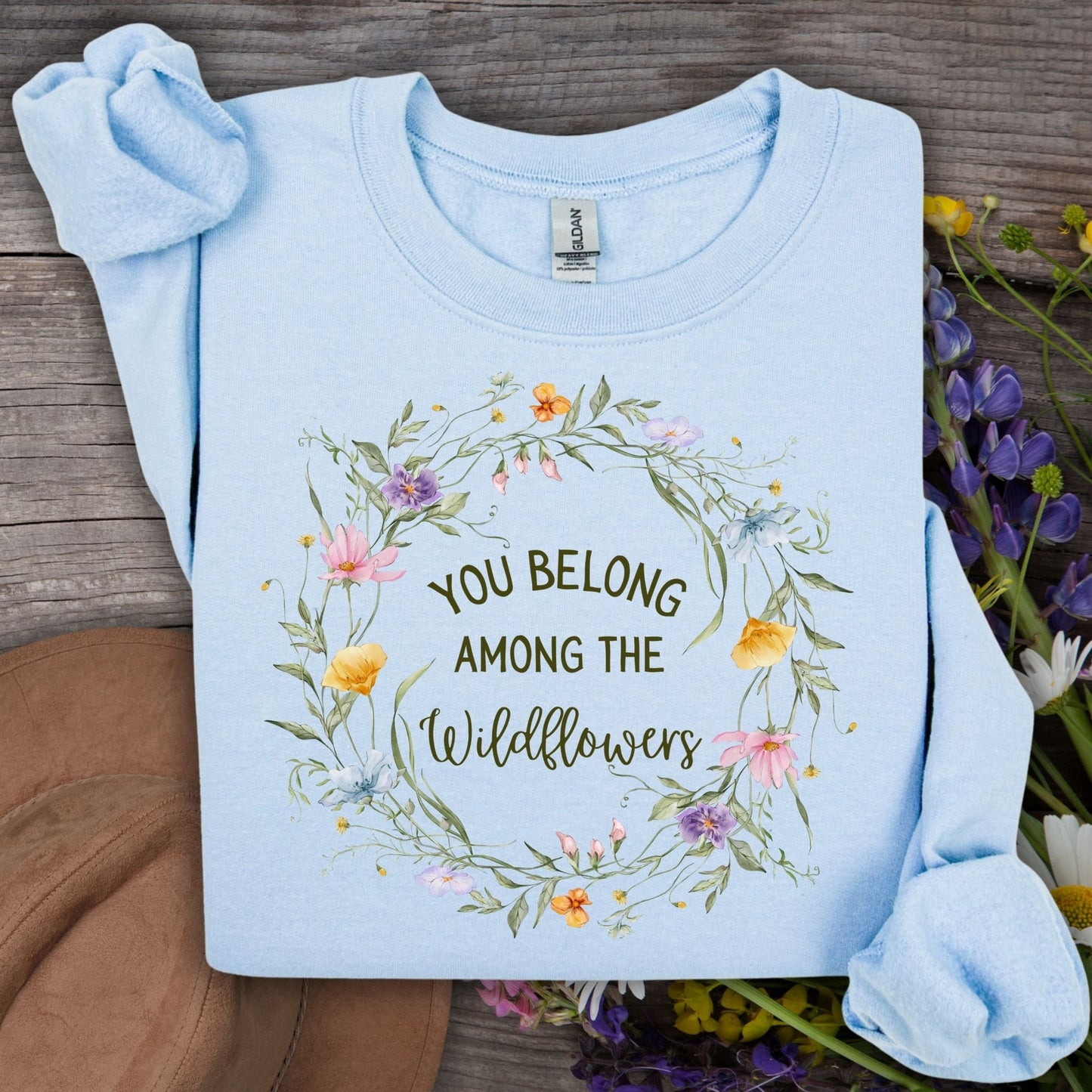 Light blue Gildan sweatshirt with "You belong among the wildflowers" in a watercolor floral wreath.