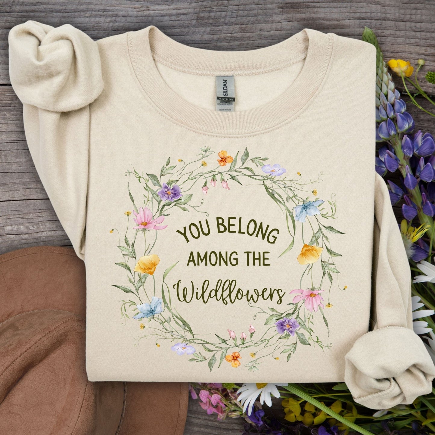 Sand Gildan crewneck sweatshirt with "You belong among the wildflowers" in a watercolor floral wreath.